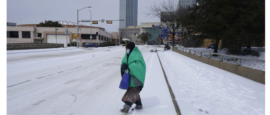 Una mujer envuelta en una manta cruza la calle cerca del centro de Dallas. / AP Photo/LM Otero,